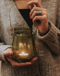 Midsection of person holding illuminated glass