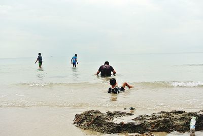 People at beach against clear sky