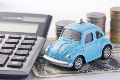 Close-up of toy car by calculator and currency against white background