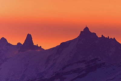 Scenic view of snow covered mountains against orange sky
