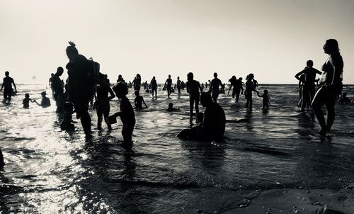 People in sea against clear sky