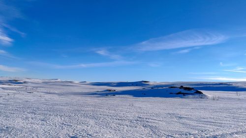 Scenic view of snowcapped landscape against blue sky