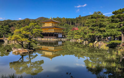 Full frame view of a golden pagoda with reflection on the water with blue skies