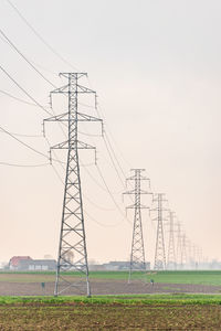 Low angle view of electricity pylon on field against sky