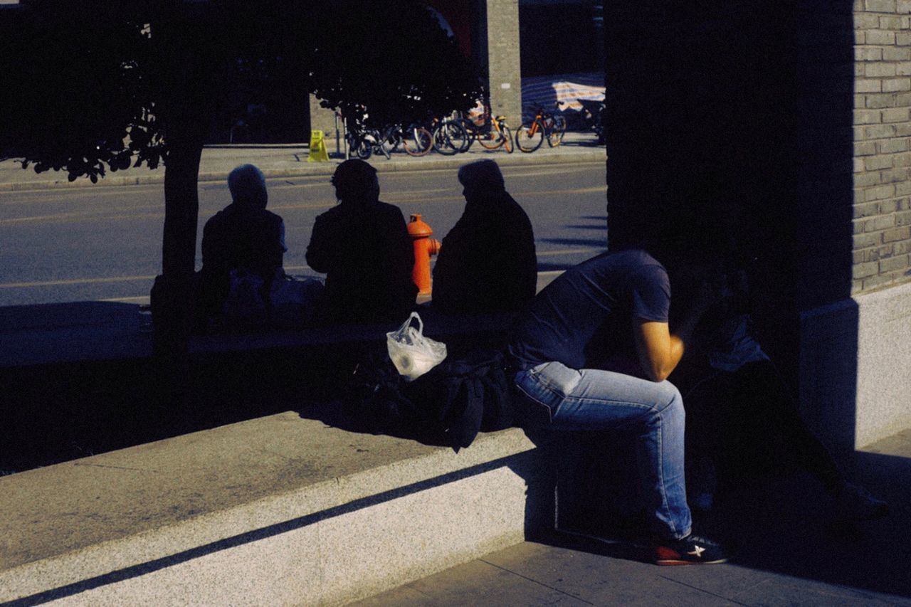 group of people, sitting, real people, people, men, transportation, architecture, full length, women, city, outdoors, nature, leisure activity, lifestyles, night, togetherness, street, shadow, waiting, warm clothing