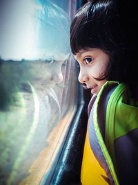 Side view of cute smiling girl looking through train window