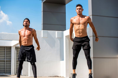 Full length of shirtless men exercising on terrace