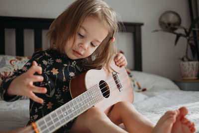 Girl playing guitar on bed