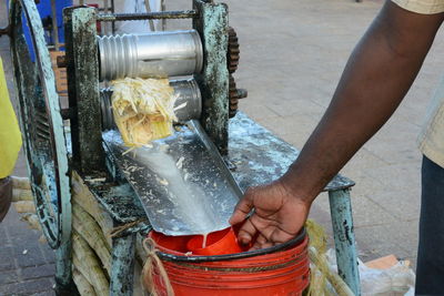 Cropped image of man cutting malung sugarcan juice