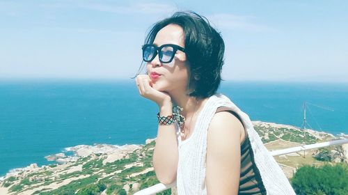 Beautiful woman wearing eyeglasses against sea on sunny day