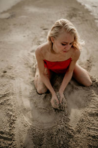 A girl in a red dress throws white sea sand