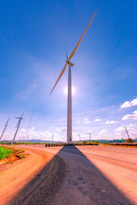 Wind turbines on road against sky