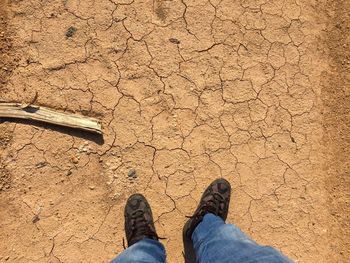 Low section of man standing on barren field