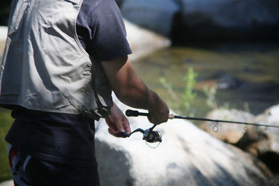 Midsection of man fishing in lake