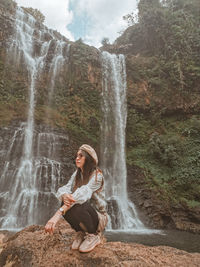 Rear view of woman standing against waterfall