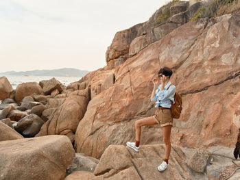 Young woman sitting on rock at beach