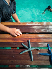 High angle midsection of man standing by wood in sea