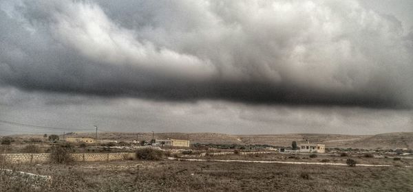 Scenic view of field against storm clouds