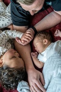 High angle view of father and baby lying on bed