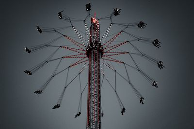 Low angle view of chain swing ride against sky