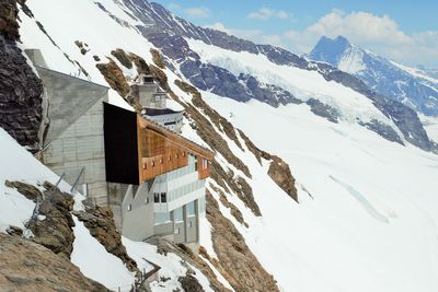 Snow covered buildings and mountains against sky