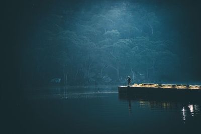 Silhouette man in lake against sky at night