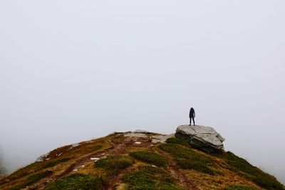 Its cloudy up in the mountains. woman on a rock.