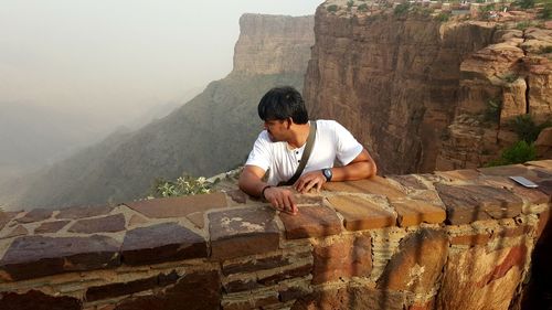 Man looking away against stone wall