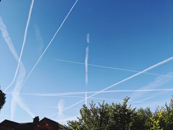 Low angle view of vapor trails against blue sky