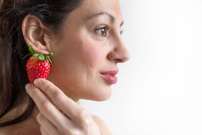 Close-up of woman holding strawberry against black background