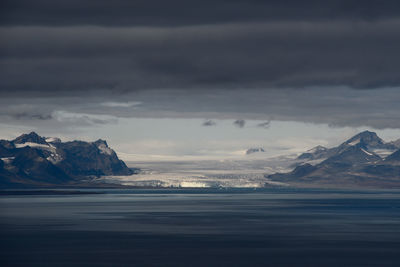 Scenic view of sea and mountains against sky during winter