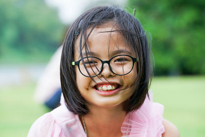 Closeup smiling face of asian girl looking at the camera with blurred natural background