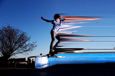 Digital composite image of teenage boy skateboarding in mid-air against clear blue sky