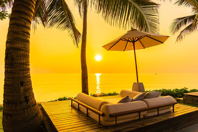 Lounge chairs by swimming pool at sunset