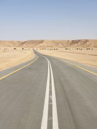 Empty road amidst desert against clear sky