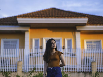 Full length of young woman standing against building