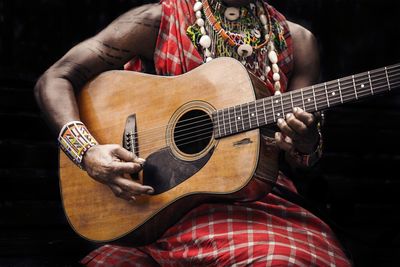 Midsection of man playing guitar