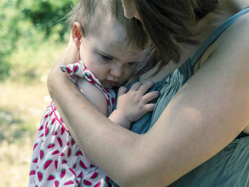 Midsection of mother carrying toddler daughter at park