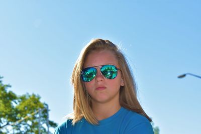 Portrait of girl wearing sunglasses against clear blue sky