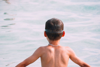 Rear view of shirtless boy in sea