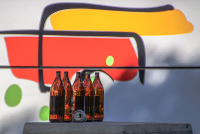 Close-up of beer bottles on table against wall