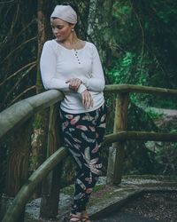 Full length of woman standing by tree in forest