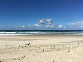 Scenic view of beach against blue sky