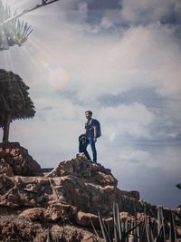 Man standing on rock against sky