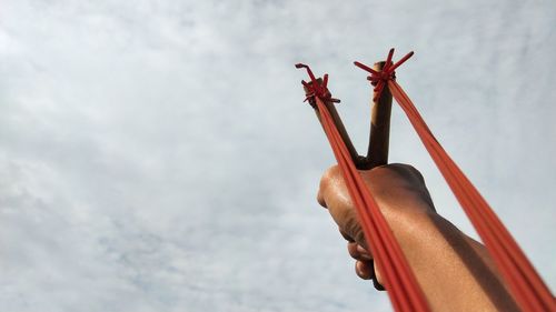 Low angle view of person hand against sky