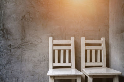 Empty white twin chairs against wall in house