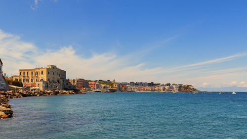 Sea by buildings against sky in city