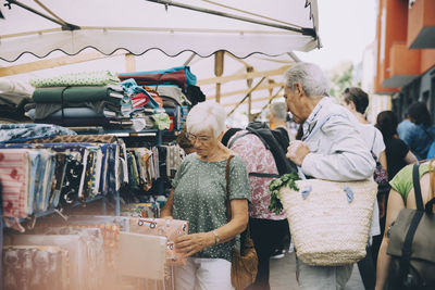 Male and female tourists shopping for textile at street market in city