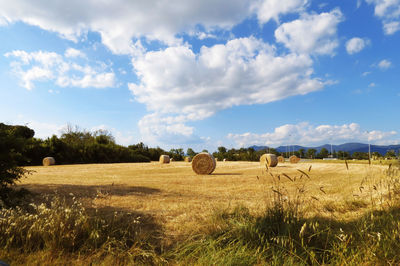 Hay bales on field against sky