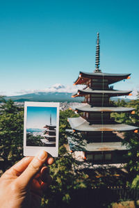 Person photographing building against clear sky